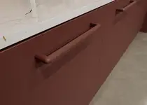 Dunkelroter, geriffelter Designgriff Soraya an gleichfarbiger Front, abgestimmt auf zahlreiche ARPA Fenix Dekore für hochwertige Möbelprojekte