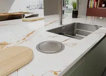 Maßgefertigte Küchenarbeitsplatte in Marmoroptik mit Edelstahlbecken und Abwurfring – Beispiel für individuell planbare Arbeitsplatten und Nischenrückwände