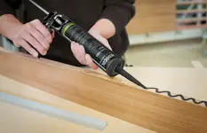 Auftragen von schwarzem MS‑Polymer‑Klebstoff auf Holzkante zur präzisen, dauerhaften Verbindung im Möbelbau