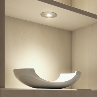 Moderne LED-Spotleuchte in Decke eingebaut, beleuchtet gezielt Regalfläche – ideal für Akzentbeleuchtung.