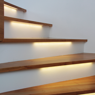 Holztreppe mit integrierten Versa LED-Bänder, die jede Stufe gleichmäßig beleuchten und für ein modernes, elegantes Ambiente sorgen.